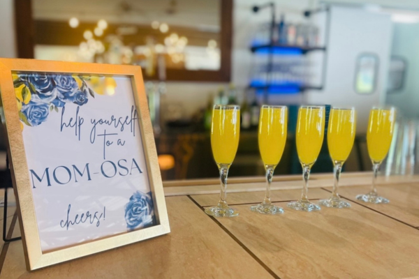 Mimosas on the bar at The Farmhouse with "help yourself to a mom-osa" sign