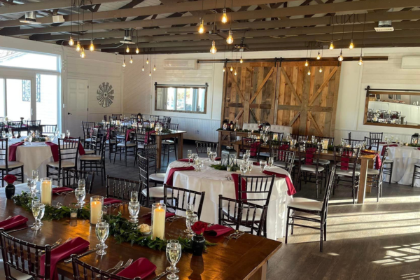 The reception room at The Farmhouse with red linens, wooden door, and rustic light fixtures