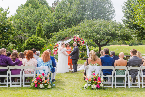 Outside wedding ceremony at the Farmhouse with lush greenery and florals