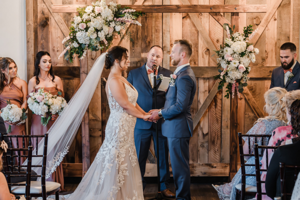 Wedding ceremony inside the Farmhouse venue with wooden and floral elements