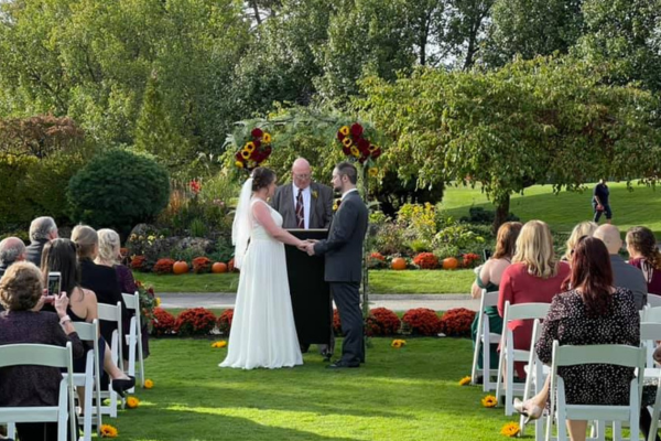 Outside wedding ceremony at the Farmhouse with lush greenery and fall foliage