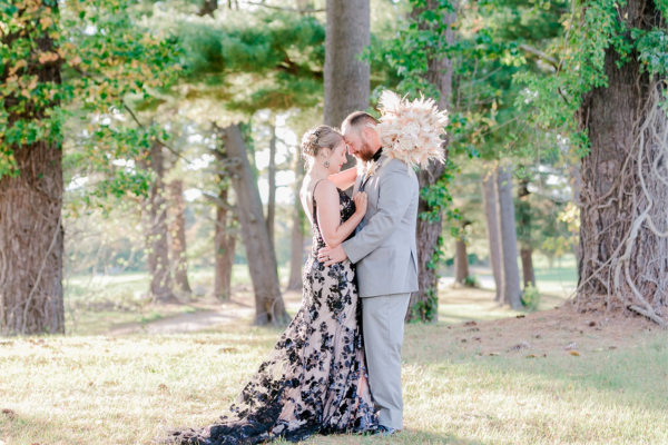 A couple posing in the wooded area of the Farmhouse