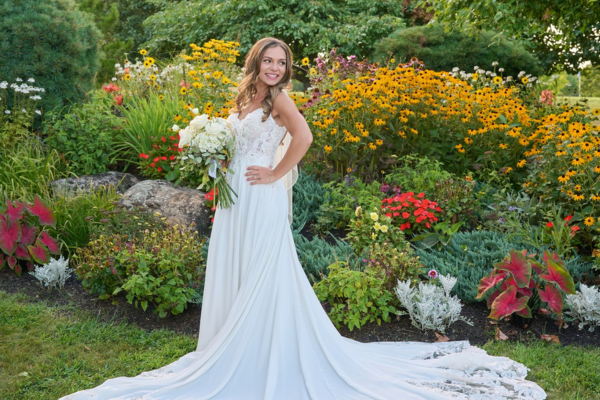 A bride standing amongst the florals and greenery at the Farmhouse